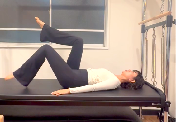 ピラティスの「トー・タップ」を行う女性