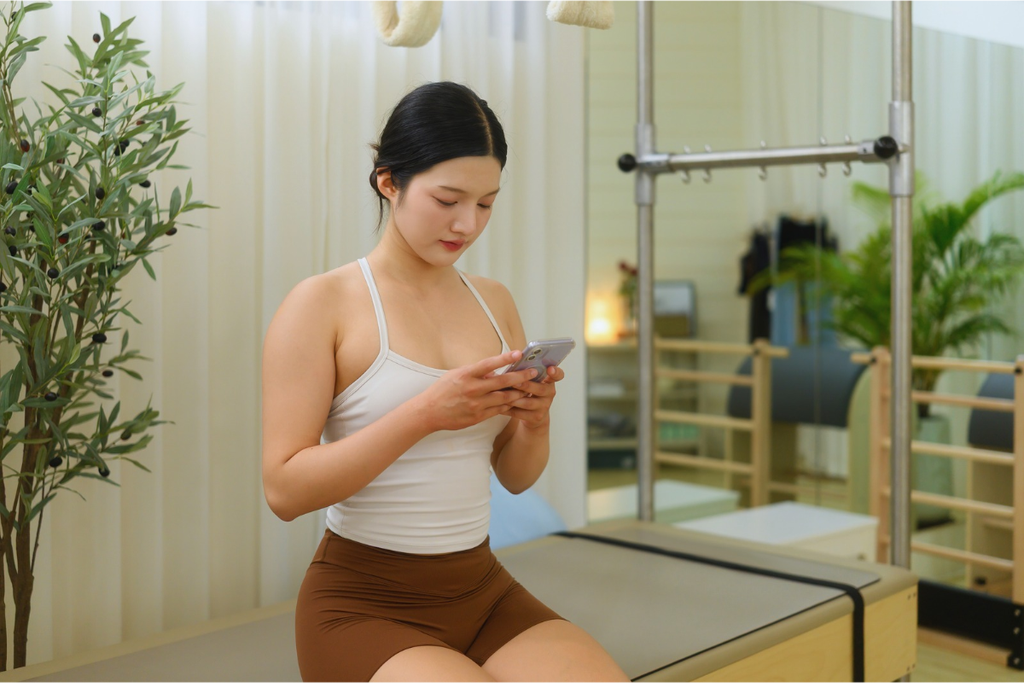 ピラティススタジオでスケジュールをスマホで確認する女性